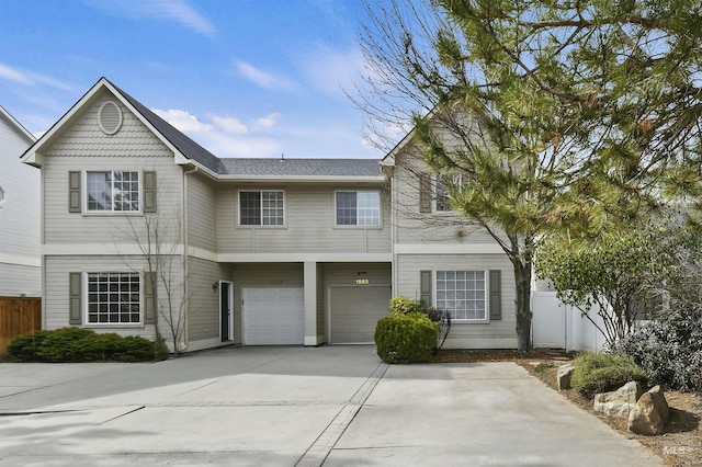 view of front facade with a garage, driveway, and fence