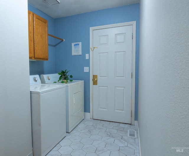washroom featuring separate washer and dryer, visible vents, and cabinet space