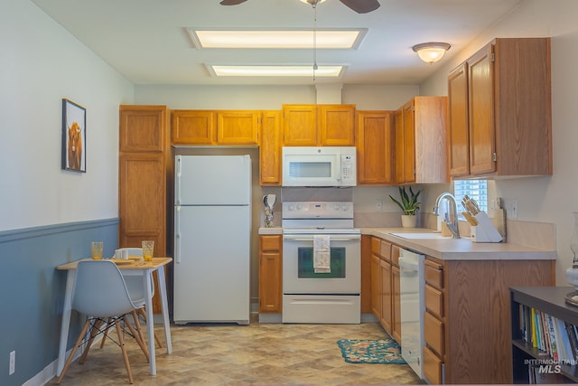 kitchen featuring a sink, white appliances, ceiling fan, brown cabinetry, and light countertops