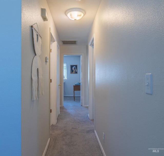 corridor with carpet, visible vents, and baseboards