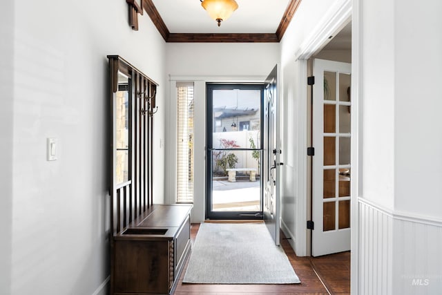 doorway featuring dark wood-style floors, ornamental molding, and wainscoting