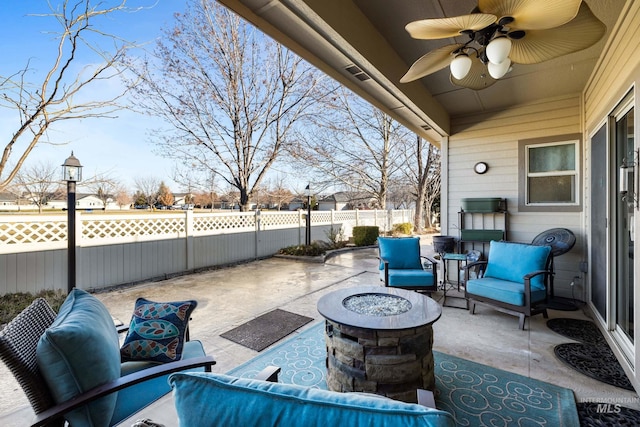 view of patio featuring an outdoor living space with a fire pit, fence, and ceiling fan