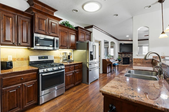 kitchen with stone countertops, dark wood-style flooring, stainless steel appliances, and a sink