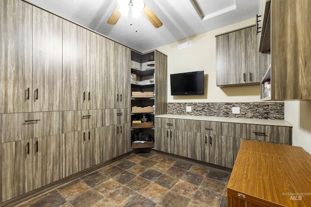 kitchen with open shelves, light countertops, backsplash, stone finish floor, and ceiling fan