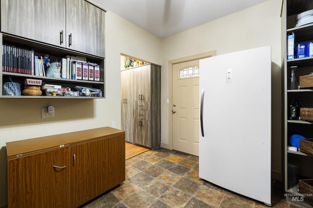 kitchen with stone finish floor and freestanding refrigerator