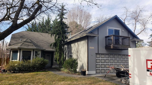 view of front of property with a garage, a front yard, and a balcony