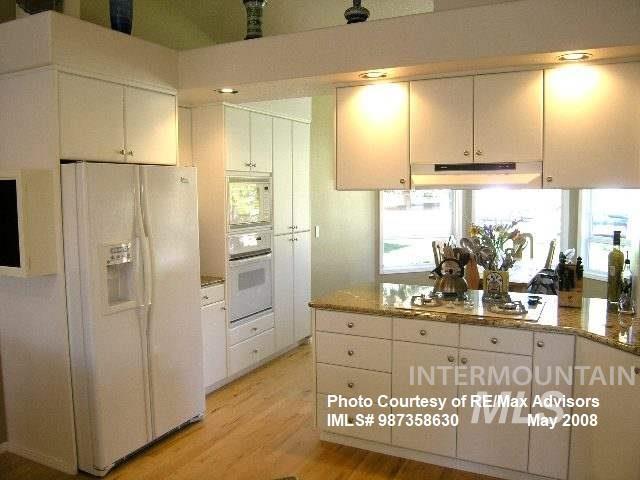 kitchen featuring under cabinet range hood, white cabinets, white appliances, and light wood-style flooring