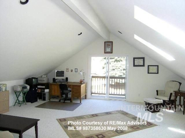 carpeted office with vaulted ceiling with beams