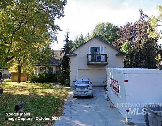 view of front of property featuring a garage, concrete driveway, a balcony, and a front yard