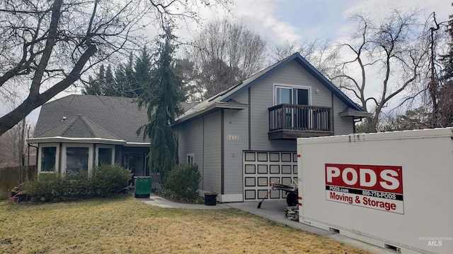 exterior space with a front lawn, a balcony, and an attached garage