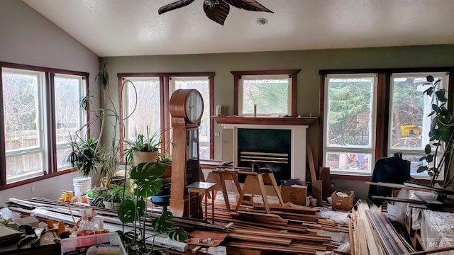 interior space with a fireplace, vaulted ceiling, and a ceiling fan