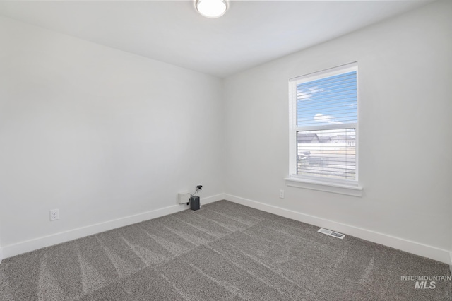spare room featuring dark colored carpet and baseboards