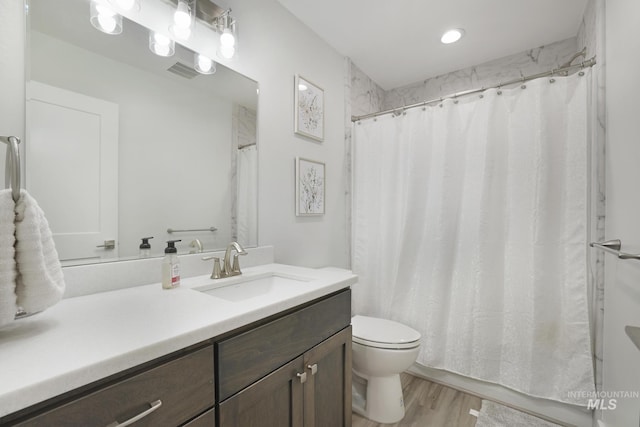 bathroom with toilet, wood finished floors, vanity, and curtained shower