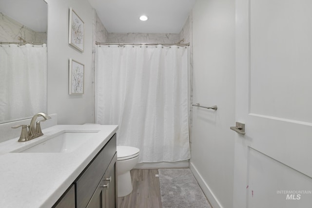 bathroom featuring toilet, vanity, curtained shower, and wood finished floors