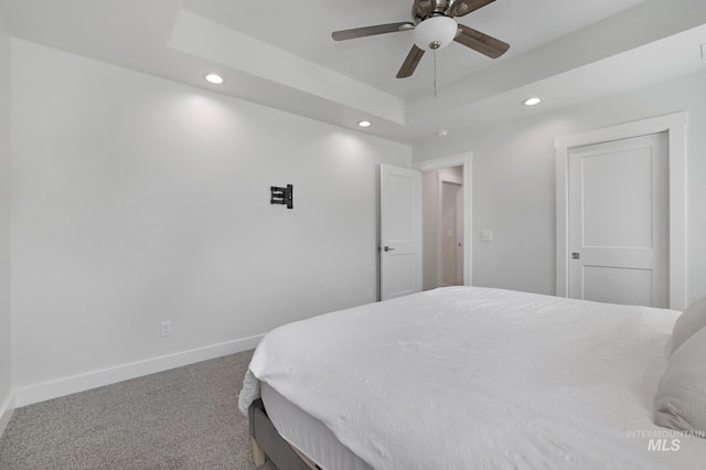 bedroom featuring recessed lighting, carpet flooring, baseboards, ceiling fan, and a tray ceiling