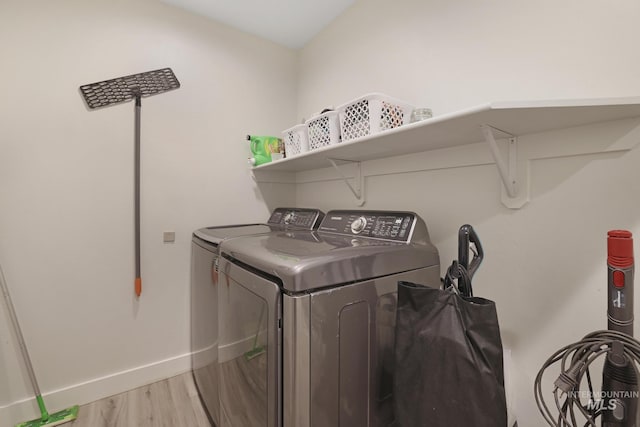 clothes washing area with light wood-type flooring, separate washer and dryer, and baseboards