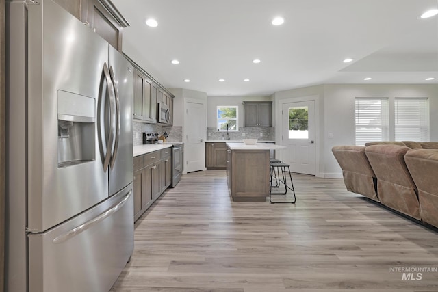 kitchen featuring stainless steel appliances, open floor plan, recessed lighting, a kitchen breakfast bar, and backsplash