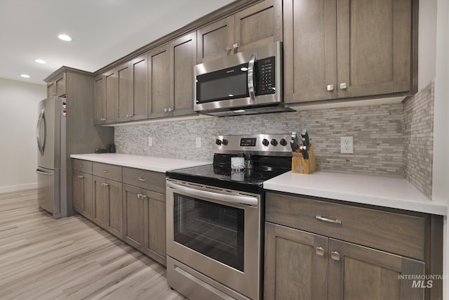 kitchen with stainless steel appliances, light wood-style floors, baseboards, tasteful backsplash, and recessed lighting