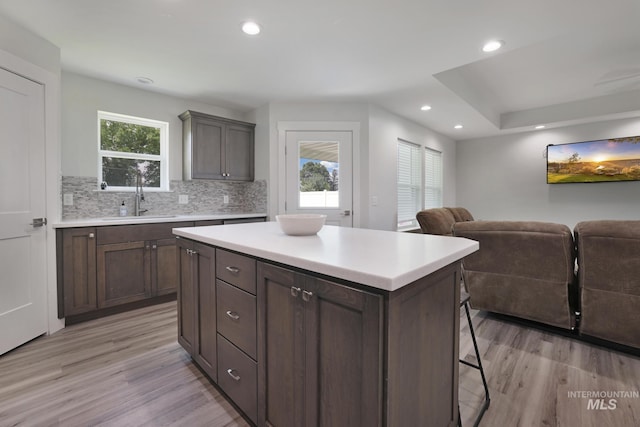 kitchen with a sink, light wood-type flooring, light countertops, a breakfast bar, and recessed lighting