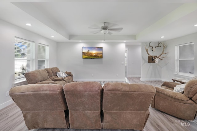 living room with baseboards, a tray ceiling, light wood finished floors, a ceiling fan, and recessed lighting