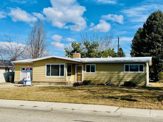 ranch-style house featuring concrete driveway, a front lawn, a chimney, and an attached garage