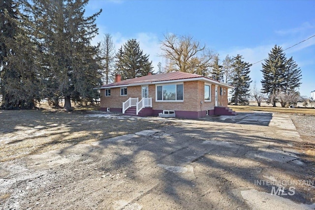 view of front of house featuring brick siding, metal roof, and a chimney