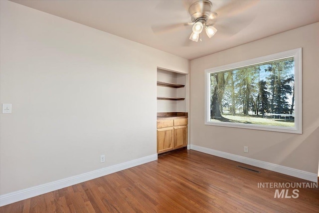 unfurnished bedroom featuring wood finished floors, visible vents, and baseboards