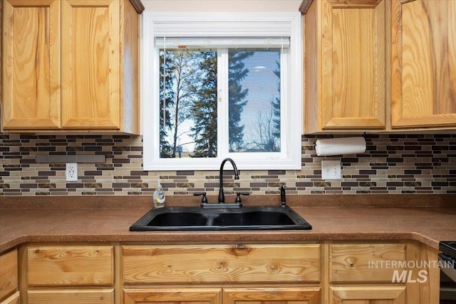 kitchen with tasteful backsplash, light brown cabinets, and a sink