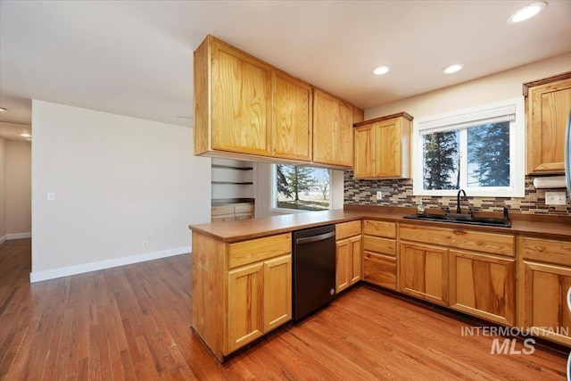 kitchen featuring dishwashing machine, tasteful backsplash, a sink, and wood finished floors