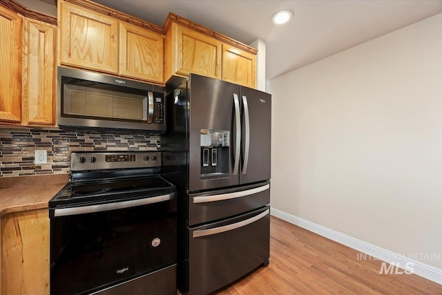 kitchen with electric range, baseboards, black fridge with ice dispenser, stainless steel microwave, and backsplash