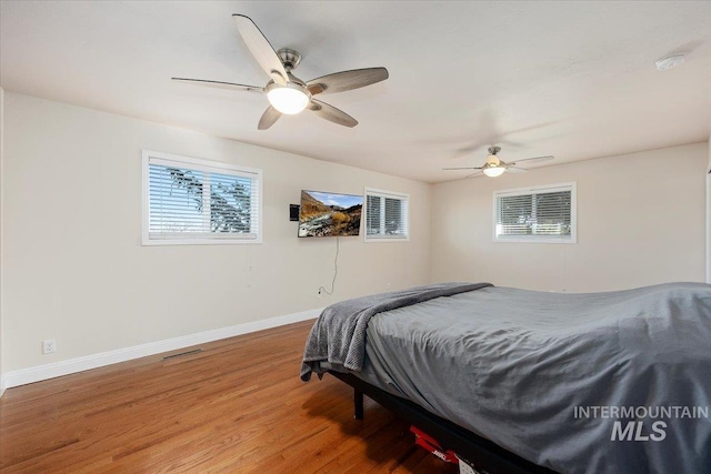 bedroom featuring ceiling fan, baseboards, and wood finished floors