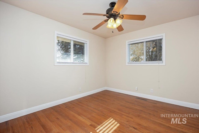 unfurnished room with ceiling fan, plenty of natural light, baseboards, and wood finished floors