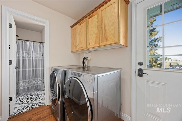 laundry area featuring cabinet space, washer and clothes dryer, and wood finished floors