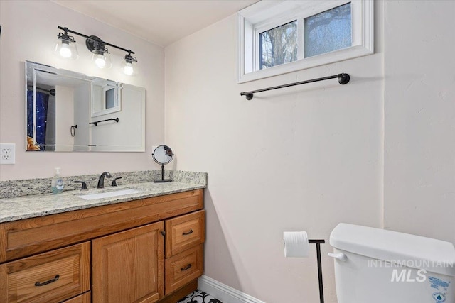 bathroom featuring toilet, vanity, and baseboards