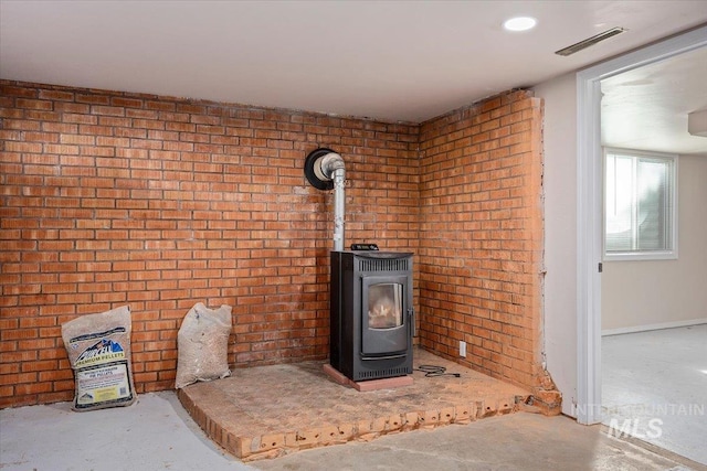 interior details with a wood stove, visible vents, and unfinished concrete flooring