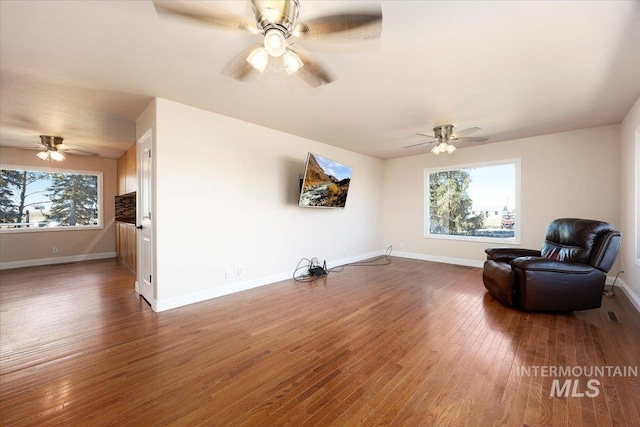 sitting room with ceiling fan, a wealth of natural light, hardwood / wood-style flooring, and baseboards