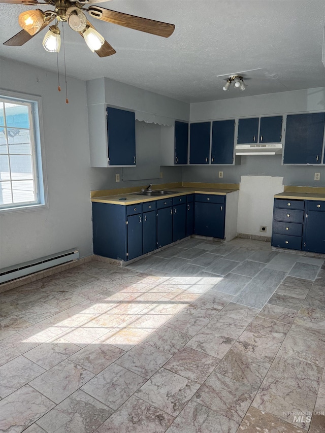 1850 18th Circle Dr, Heyburn, ID 83336 - kitchen featuring blue cabinetry, a sink, under cabinet range hood, a baseboard radiator, and a textured ceiling