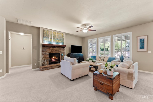 living room with baseboards, a stone fireplace, a ceiling fan, and light colored carpet