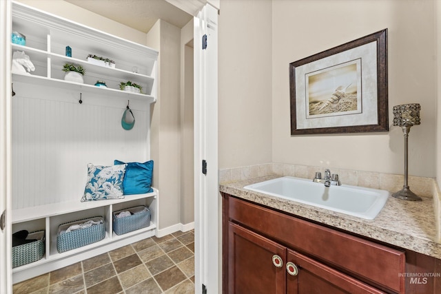 mudroom with a sink, dark stone finish floors, and baseboards