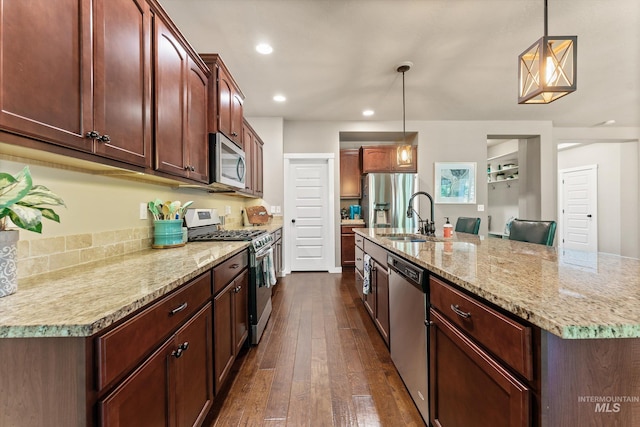 kitchen featuring stainless steel appliances, a sink, dark wood-style floors, recessed lighting, and hanging light fixtures