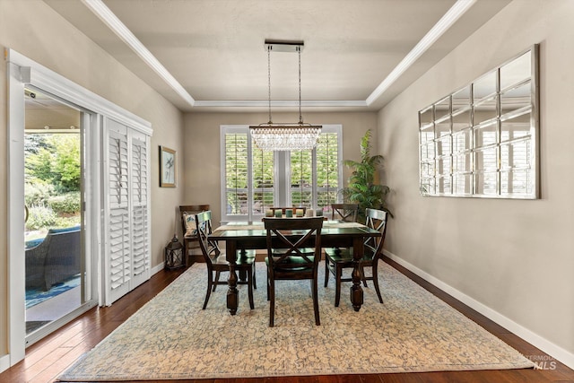 dining space with a raised ceiling, baseboards, dark wood-style floors, and a chandelier