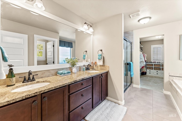 bathroom featuring a stall shower, tile patterned floors, double vanity, a bath, and baseboards