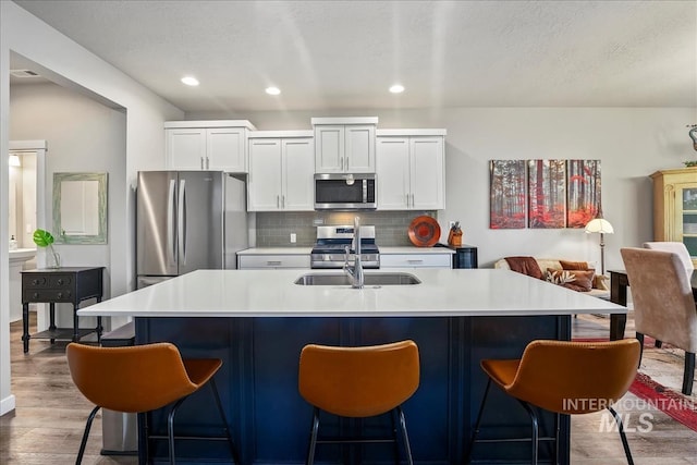 4084 E Esperanto St, Meridian, ID 83642 - kitchen with light wood-type flooring, white cabinetry, appliances with stainless steel finishes, a sink, and decorative backsplash