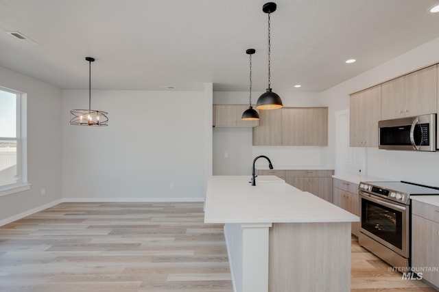 kitchen featuring stainless steel appliances, light countertops, light brown cabinets, a sink, and modern cabinets