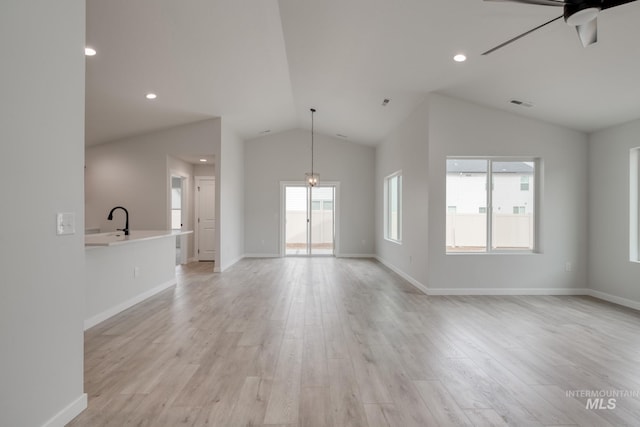 unfurnished living room featuring baseboards, light wood-style flooring, ceiling fan, and vaulted ceiling