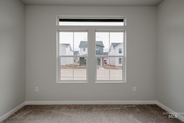 spare room featuring carpet flooring, baseboards, and a healthy amount of sunlight