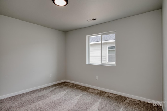 spare room featuring carpet, visible vents, and baseboards