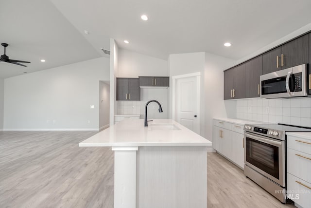 kitchen featuring a sink, lofted ceiling, tasteful backsplash, light countertops, and appliances with stainless steel finishes