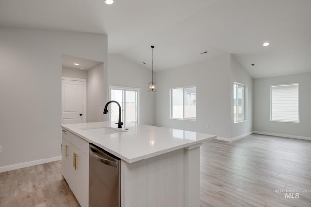 kitchen with light wood finished floors, an island with sink, a sink, dishwasher, and vaulted ceiling