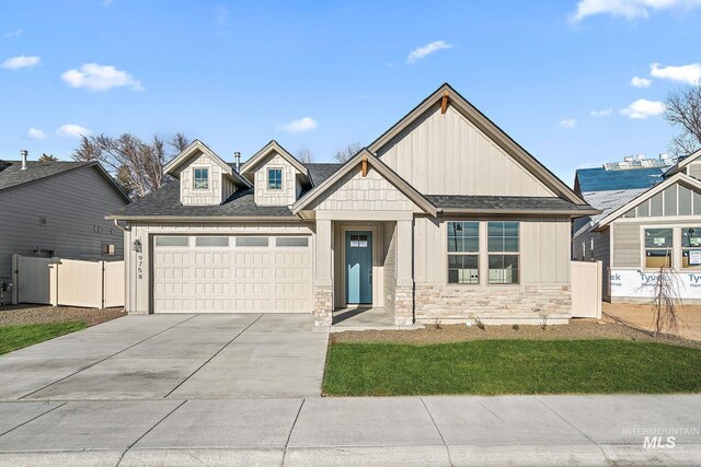 view of front of home featuring fence, stone siding, board and batten siding, an attached garage, and driveway